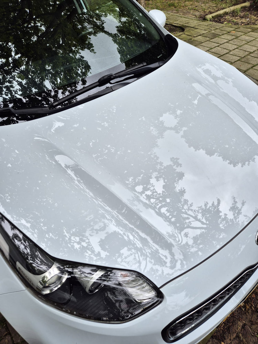 Schuim op de motorkap van een witte auto