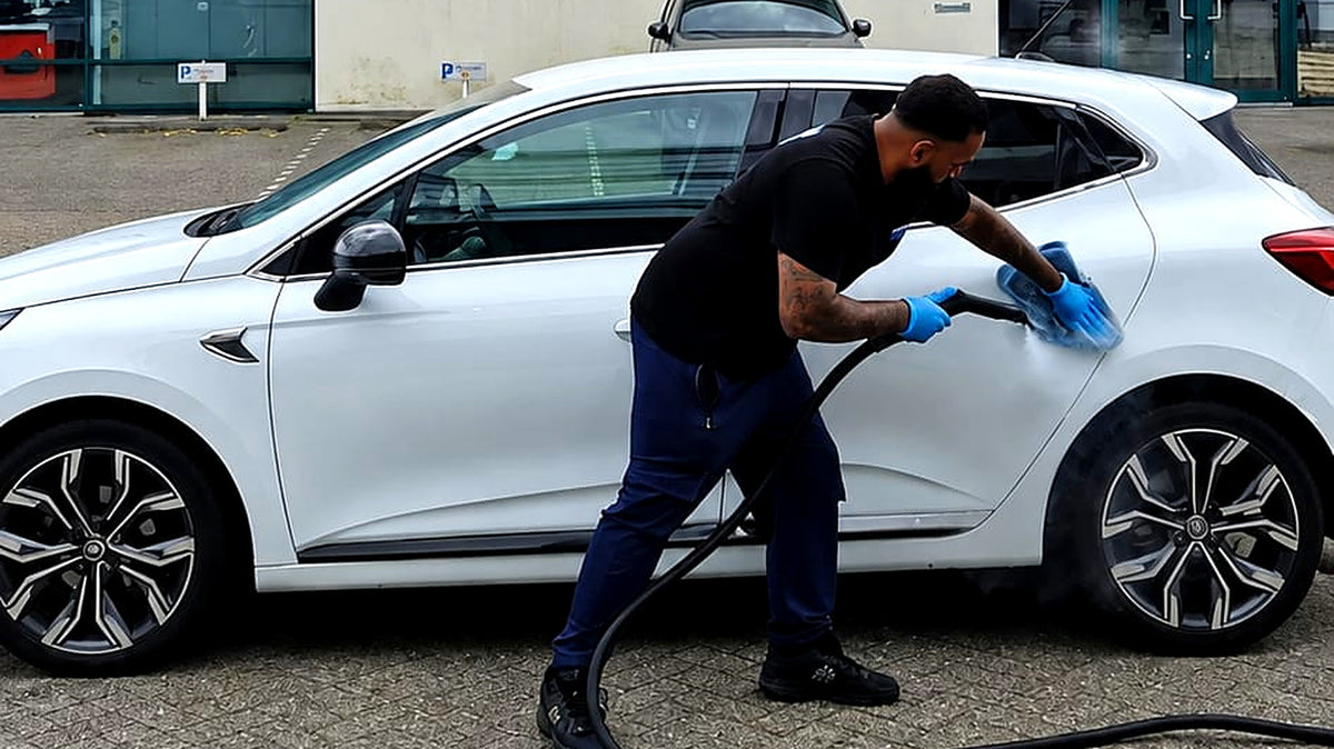 Medewerker van Auto Schoon Nederland maakt een witte Renault Clio schoon met stoom