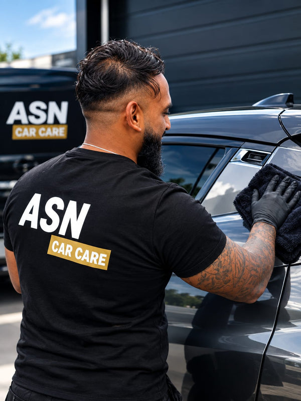 Medewerker van ASN Car Care droogt een donkergrijze auto na met een microvezeldoek